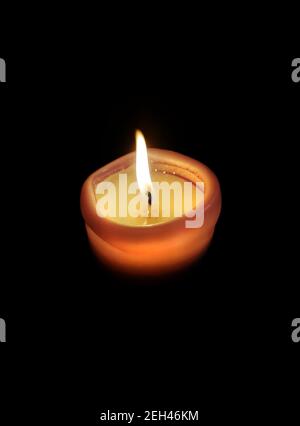Single lit candle with quite flame on black background. Candle burning at night. Vertical shot. Stock Photo