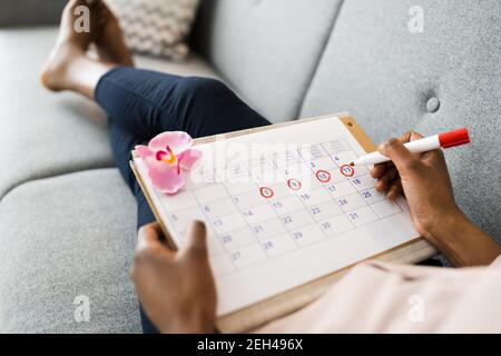 African Woman Using Menstrual Cycle Or Period Calendar Stock Photo