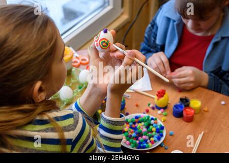 Children at the table are painting Easter eggs for the holiday Stock Photo
