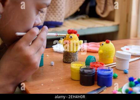 Girl gently paints Easter eggs with a brush and paints Stock Photo