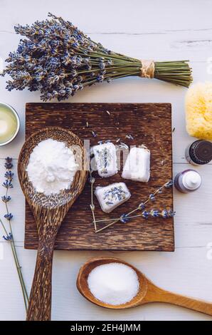 Flat lay view of small cube shape bathroom bath fizzies on wood tray, surrounded by ingredients. Making homemade small bath fizzy. Stock Photo