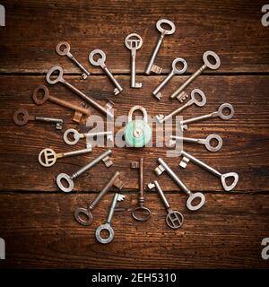 Vintage rusty padlock surrounded by group of old keys on a weathered wooden background. Internet security and data protection concept, blockchain and Stock Photo
