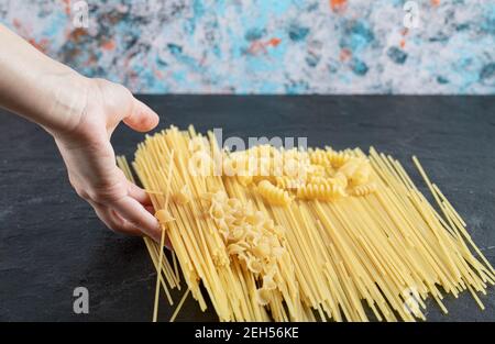 Female hands touching various pasta on dark surface Stock Photo