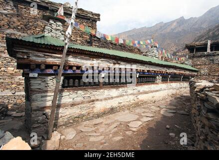 Buddhist prayer many wall with prayer wheels in nepalese village, round Annapurna circuit trekking route, Nepal Stock Photo