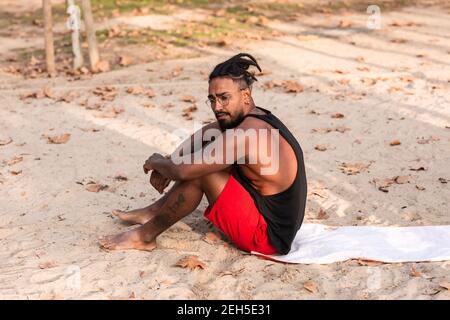 sports guy is sitting on a towel in a park, usually sand. he is african american Stock Photo