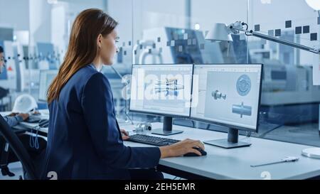 Portrait of Young and Confident Industrial Engineer Working on Computer, on Screen CAD Software Showing New Generation Electric Engine. Industrial Stock Photo