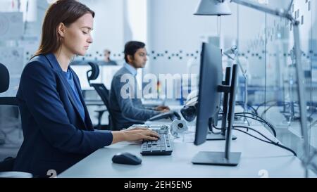 Portrait of Young and Confident Industrial Engineer Working on Computer. Industrial Factory with High-Tech CNC Machinery Stock Photo