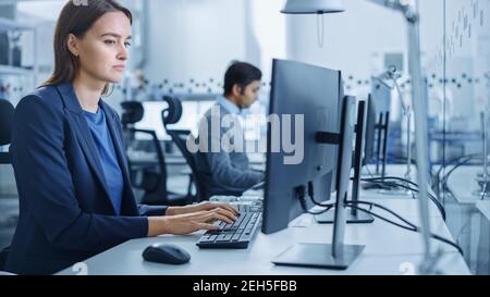 Portrait of Young and Confident Industrial Engineer Working on Computer. Industrial Factory with High-Tech CNC Machinery Stock Photo