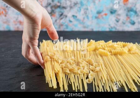 Female hands touching various pasta on dark surface Stock Photo
