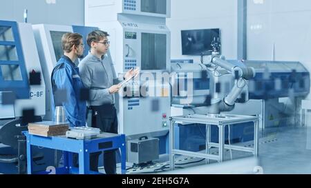 In Factory Workshop: Workers Use High-Tech Industrial CNC Machinery, Robot Arm. Inside Office: Digital Engineering Professional Working on Personal Stock Photo