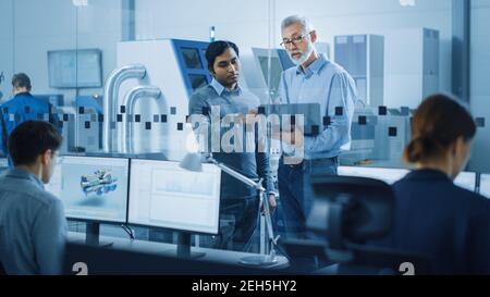 Automotive Design Factory: Project Manager, Chief Mechanical Engineer Talk, Use Laptop, Discuss Project Details. High-Tech Industrial Facility Stock Photo