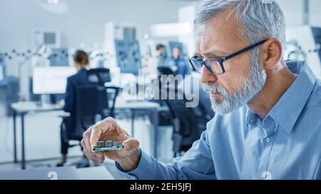 Electronics Design Factory Office: Electrical Engineer Working on Computers, using CAD Software to Develop Microchips, Semiconductor Stock Photo