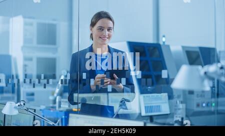 Modern Factory Office: Portrait of Young and Confident Female Industrial Engineer Standing and Holding Digital Tablet. Industrial Factory Office with Stock Photo