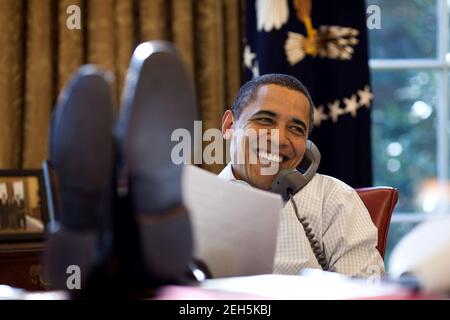 President Barack Obama smiles while talking with Russian President Dmitry Medvedev on the phone in the Oval Office, Saturday, Dec. 12, 2009. Stock Photo