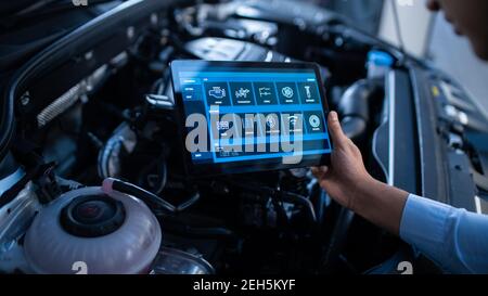 Car Service Manager or Mechanic Uses a Tablet Computer with a Futuristic Interactive Diagnostics Software. Specialist Inspecting the Vehicle in Order Stock Photo