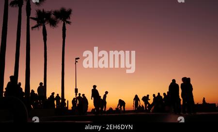 Silhouette of young jumping skateboarder riding longboard, summer sunset background. Venice Ocean Beach skatepark, Los Angeles California. Teens on sk Stock Photo