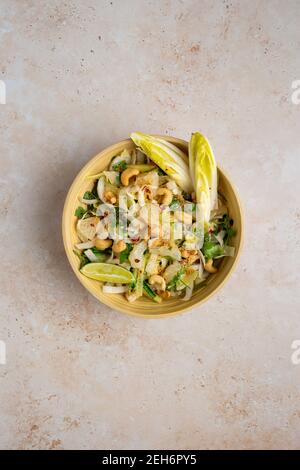 Top down view of a delicious vegan Bali style pomelo salad with chicory, cucumber, cashews, coriander , toasted coconut and chill lime dressing Stock Photo