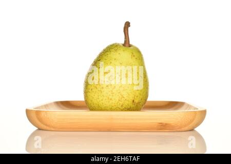 One whole ripe juicy tasty pear Lucas lies on a bamboo tray, on a white background. Stock Photo