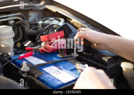 Car battery repair and inspection. The man measures the voltage and capacity of the battery with a tester. Car service. Stock Photo