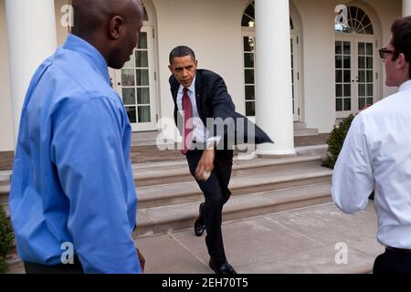 President Barack Obama practices his pitching form with personal aide Reggie Love and Jake Levine in the Rose Garden of the White House, March 31, 2010. Later that day, the President threw out the first pitch on opening day of the baseball season prior to the game between the Washington Nationals and the Philadelphia Phillies.   This official White House photograph is being made available only for publication by news organizations and/or for personal use printing by the subject(s) of the photograph. The photograph may not be manipulated in any way and may not be used in commercial or political Stock Photo