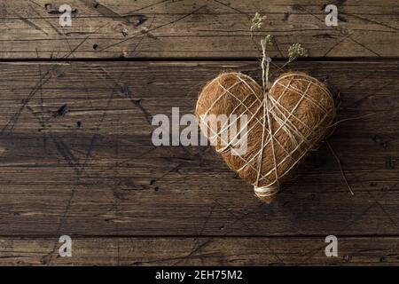 Straw heart hanging on a nail on a wooden wall, rustic style, space Stock Photo