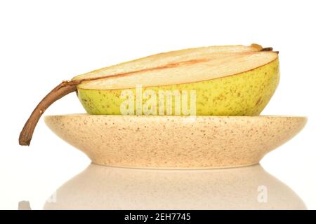 One half ripe juicy tasty Lucas pear lies on a ceramic saucer, on a white background. Stock Photo