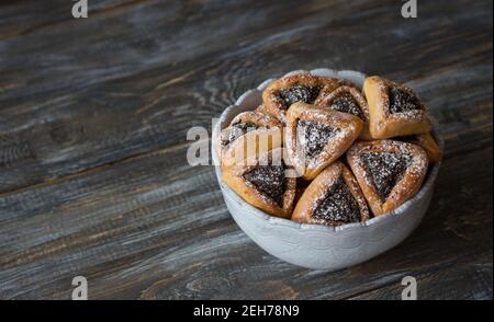 Homemade hamantashen cookies (Haman's ears) with poppy seeds and apples on a wooden background. Traditional pastries for celebrating Purim, Jewish car Stock Photo