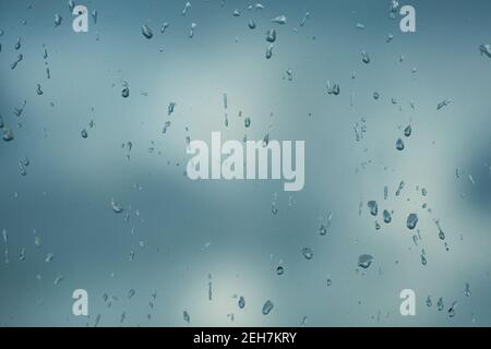 Rain drops on window with blured gray background. Seasonal background texture for design. Stock Photo