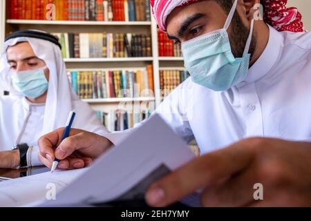 Arabic guys studying for exam together wearing protection masks