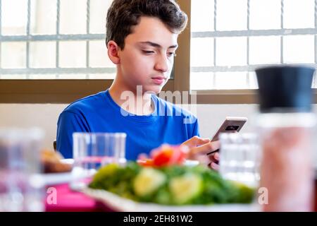 Arabic Muslim boys using their smartphones while eating and taking photos of the food Stock Photo