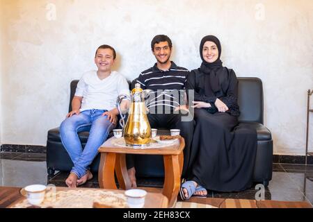 Happy Arabic family sitting together enjoying Arabic coffee and sweets and talking to each other Stock Photo