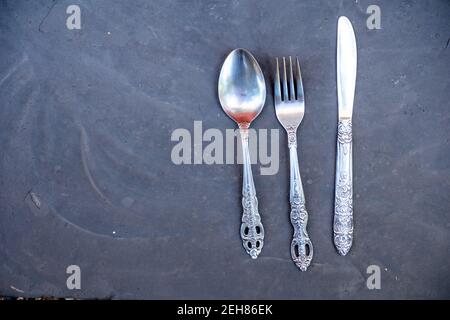 Kitchenware spoon and knife and fork with black gray background Stock Photo