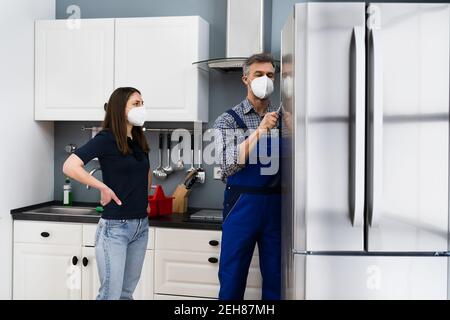 Fridge Repair Service. Refrigerator Repairman Technician In Face Mask Stock Photo