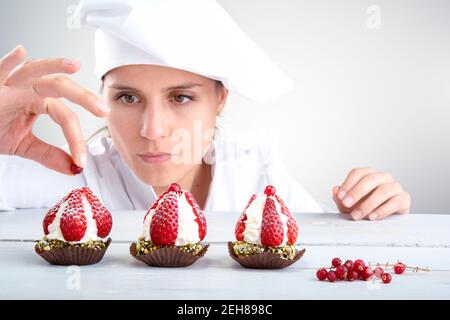 woman cook perfectly decorates small strawberry cupcakes Stock Photo