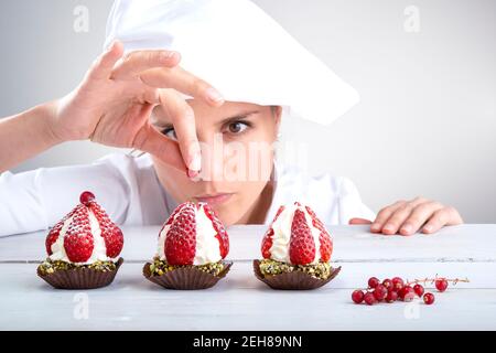 woman pastry chef decorates small strawberry cakes Stock Photo