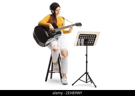 Young female playing an acoustic guitar with a music note stand isolated on white background Stock Photo