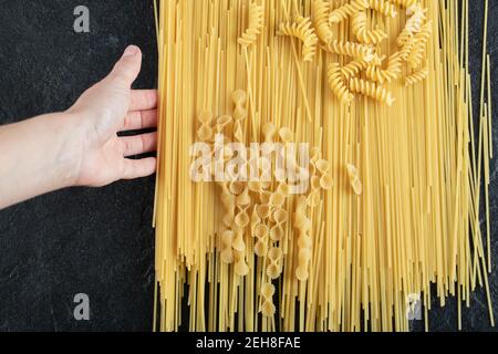 Woman hands touching various pasta on dark surface Stock Photo