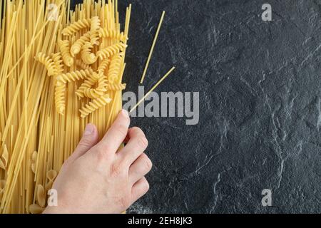 Female hands touching various pasta on dark surface Stock Photo