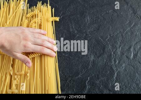 Female hands touching various pasta on dark surface Stock Photo