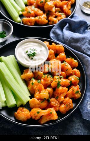 Close up view of cauliflower buffalo wings with celery and sauce. Healthy eating, plant based food concept. Stock Photo