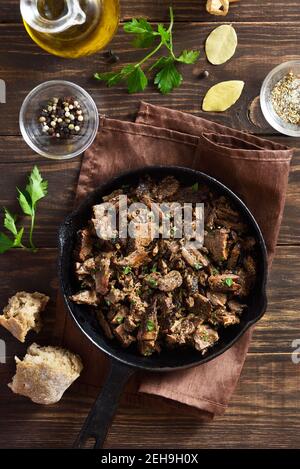 Slow cooked pulled beef in frying pan on wooden background. Top view, flat lay Stock Photo