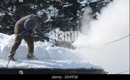 Mount Pleasant, Wisconsin, USA. 19th Feb, 2021. CHRIS HANSON uses steam to clear snow from the roof and gutters of a home in the Village of Mount Pleasant, Wisconsin Friday February 19, 2021. The area received almost 17'' of snow last Sunday and Monday. (Credit Image: © Mark HertzbergZUMA Wire) Stock Photo
