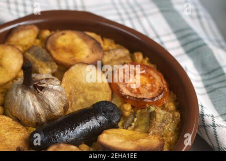 Image of a clay casserole in which typical Mediterranean baked rice has been cooked with black pudding, tomatoes, potatoes, chickpeas ... Stock Photo