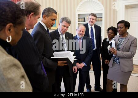 President Barack Obama receives a leather-bound 2009 edition of the 'Public Papers of the Presidents of the United States' from David S. Ferriero, Archivist of the United States, center, in the Oval Office, Feb. 25, 2011. Joining them are staff from the Office of the Federal Register and National Archives and Records Administration. Stock Photo