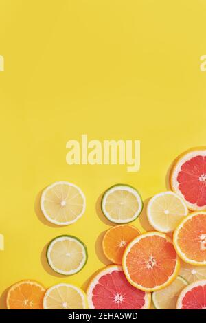 Flat lay made of different citrus fruits slices on yellow background with copy space. Stock Photo