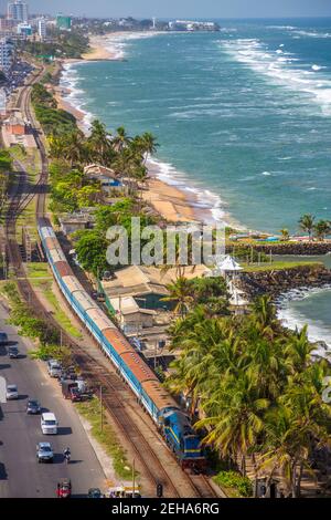 Aerial of public train along the waterfront and Wellawathth Beach, Colombo, Sri Lanka. Colombo is the commercial capital and largest city of Sri Lanka Stock Photo