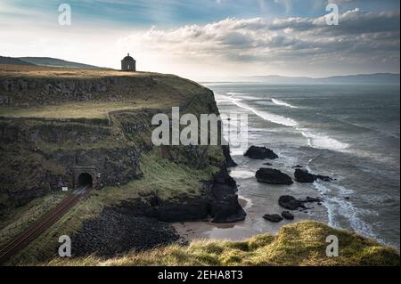 Railway line running along the Causeway Coast in Northern Ireland. A tunnel goes under the Musseden Temple Stock Photo