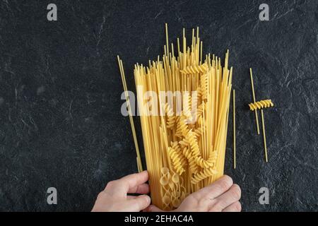 Woman hands touching various pasta on dark surface Stock Photo