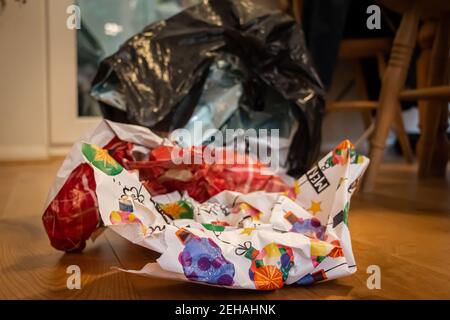 Christmas wrapping paper waste in a bin liner lying on a wooden floor on Christmas day, after presents had been open Stock Photo