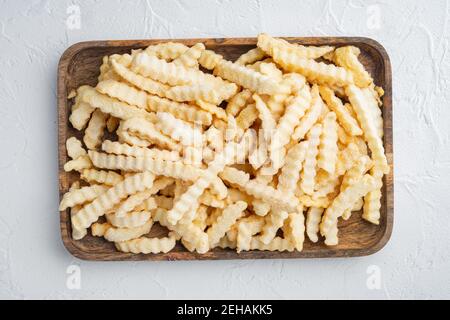 https://l450v.alamy.com/450v/2ehakk5/frozen-crinkle-oven-fries-set-on-wooden-tray-on-white-background-top-view-flat-lay-2ehakk5.jpg